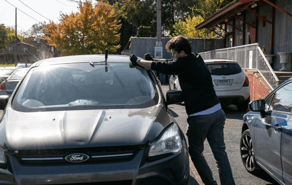 Man repairing windshield on parked car
