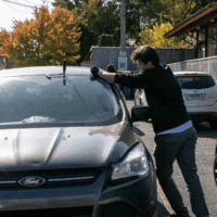 Man repairing windshield on parked car