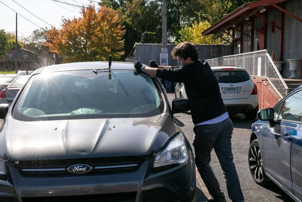 Man repairing windshield on parked car